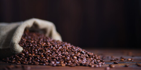 Fototapeta premium Close-up view of a burlap sack spilling rich coffee beans, representing warmth and generosity. Ideal for coffee enthusiasts and rustic themes.