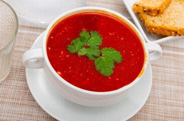 Just prepared portion of red beetroot soup, svekolnik, served on table with parsley.