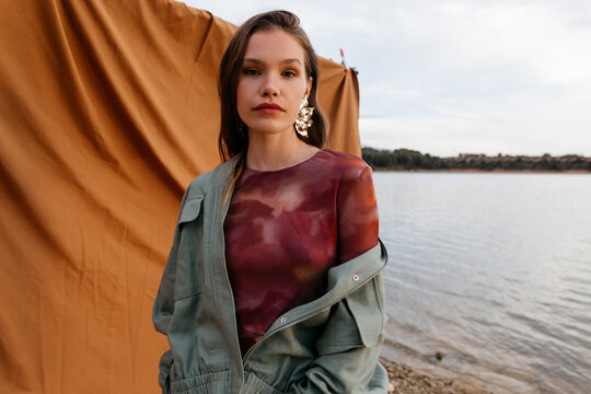 Model standing near rippling lake water
