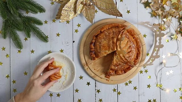 The girl places the bitten piece of the royal galette in a saucer on the table.