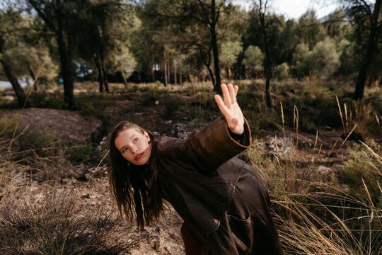 Young woman in long coat on grassy ground