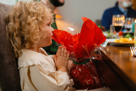 A girl prays while sitting at a festive table