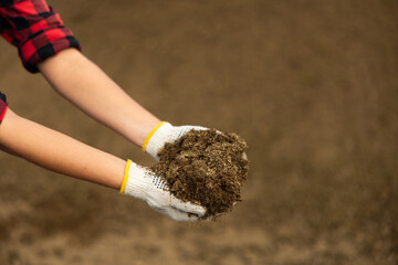 Worker's hands in gloves hold handful of dry crushed manure close-up