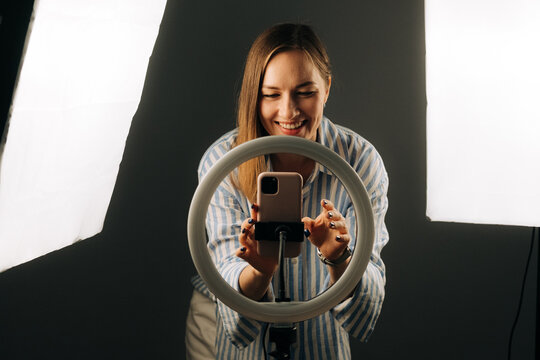 Woman setting up smartphone on ring light for recording