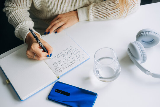 Close-Up of Female Hands Writing in Notebook