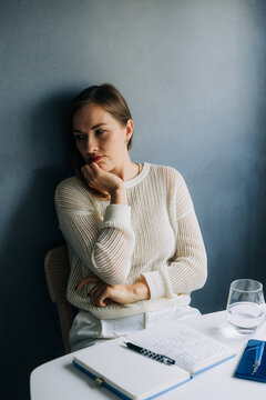 Woman leaning on hand, appearing pensive and thoughtful indoors