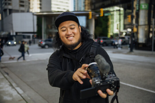 Man Recording Video Content on Urban Street with Camera