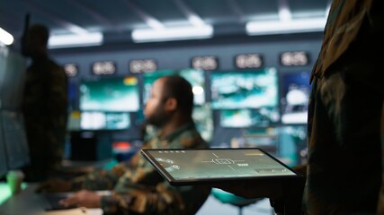 Army operative using tablet in command center housing operational missile defense system designed to intercept ballistic rockets. Close up of expert using tracking software on device, camera B