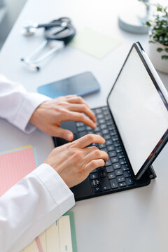 The doctor uses a laptop with white screen