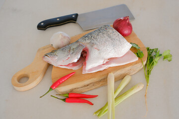 Fresh snapper fish on a wooden cutting board in a kitchen with a knife nearby