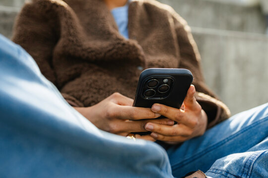 A woman uses a mobile phone while sitting outdoors