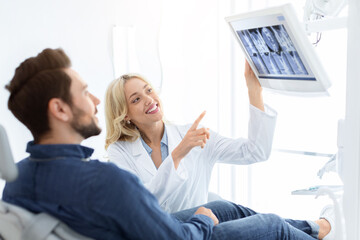 Modern technologies and dentistry. Pretty woman dentist having conversation with male patient...