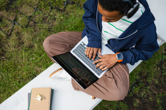 A man uses a laptop while sitting outdoors