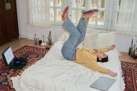 A young woman enjoys a playful moment on her bed 