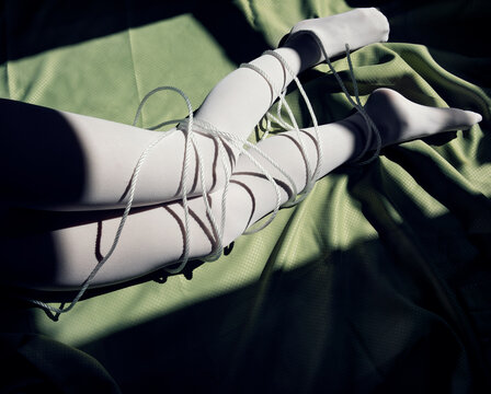 legs in white stockings wrapped with white cord in window light