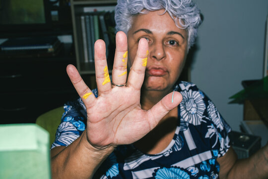Elderly woman showing hand with colorful paint