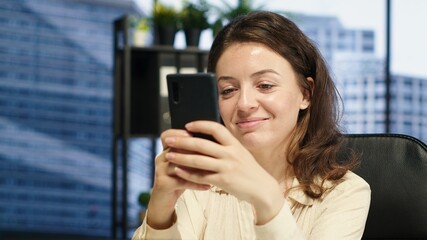 Pleased empowered businesswoman texting messages in her own director office, having fun on social media. Leader discussing with partners about new project ideas for career growth. Camera A.