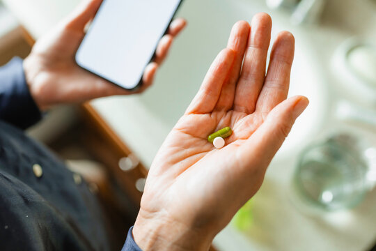  The woman uses a mobile phone with white screen and takes pills