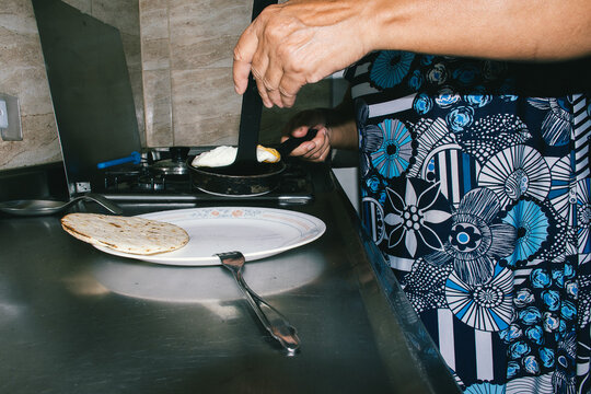 Elderly woman cooking traditional arepa