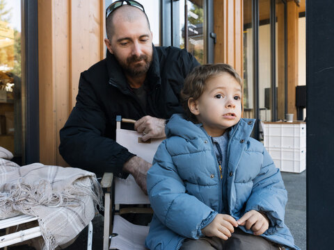 Stylish Todler Sitting On The Veranda Of A Street Cafe