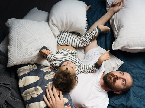 Father And Son Resting Lying On The Bed