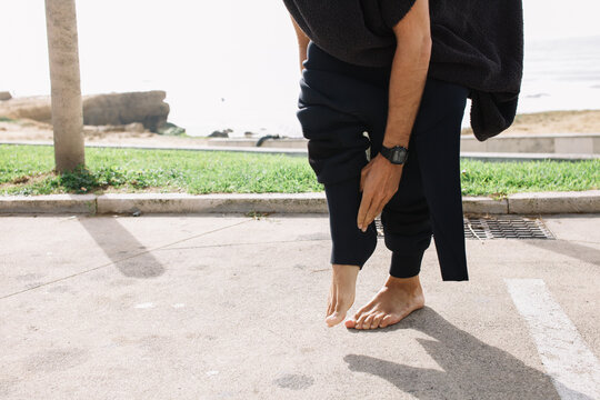 A young guy putting a wetsuit on