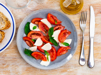 Delicious fresh vegetable caprese salad with tomato and mozzarella served on plate