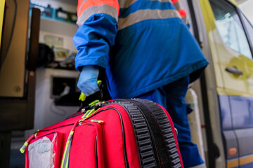 Paramedic carrying emergency medical bag from ambulance