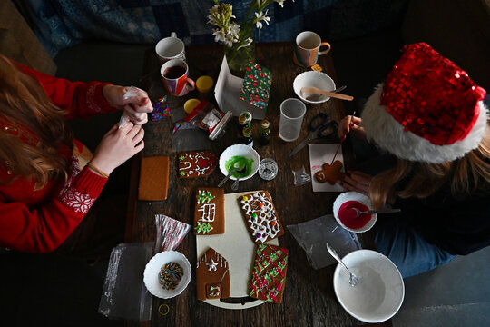 Two girls make a gingerbread house together