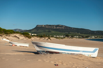 White fishing boat tied on sandy shore