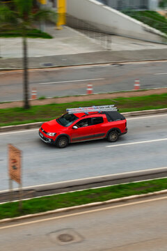 Red Volkswagen Saveiro Cross on a city road - Panning shot of a modern light pickup truck