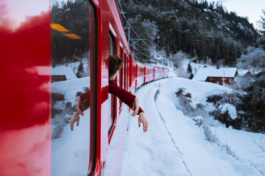 Woman traveling in red train and looking out the window