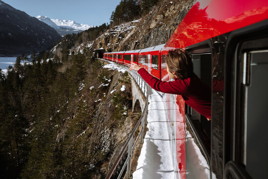 Woman traveling in red train and looking out the window