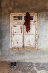 Khan Sahib Tehsil, Jammu and Kashmir, India. Peeling white paint on a wooden shuttered window.
