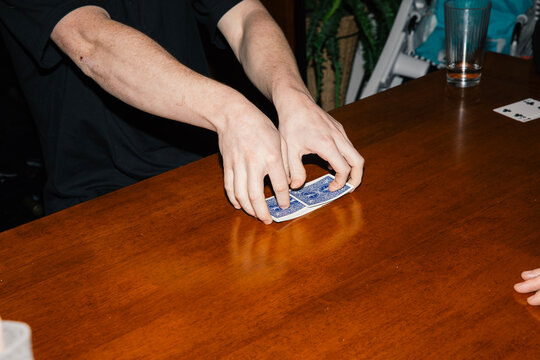 Anonymous young man shuffling small pile of playing cards