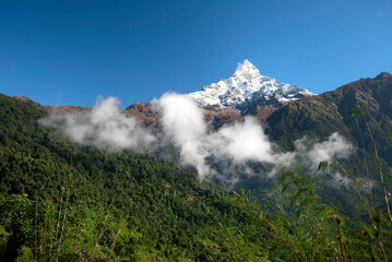 Nepal. Machapuchare Mountain above the clouds and Annapurna Range.