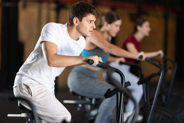 Guy in sportswear trains on an airbike in a gym. European man at cardio workout in the Crossfit gym