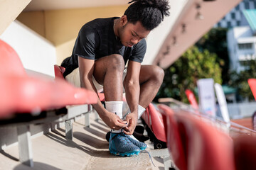 Male soccer player tying shoelace at stadium