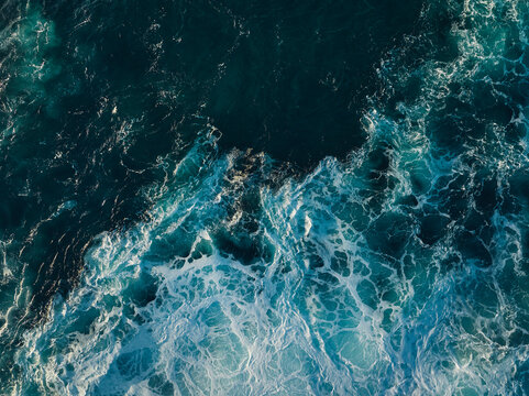 Top down aerial view of ocean wave crashing on coastline at sunset  - Powered by Adobe