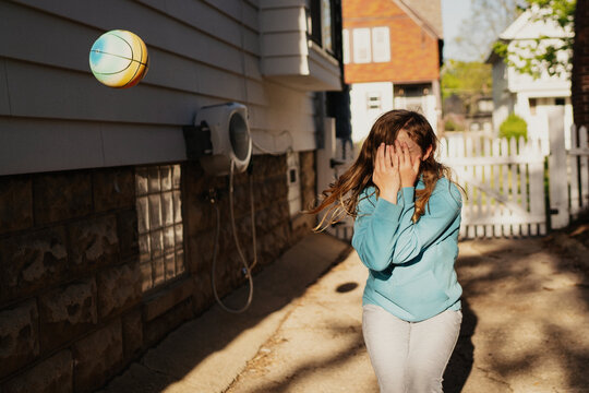 Girl shielding face from thrown ball
