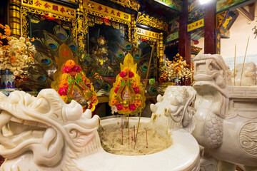 Vietnam. Temple with traditional altar based on dragon design with incense sticks.