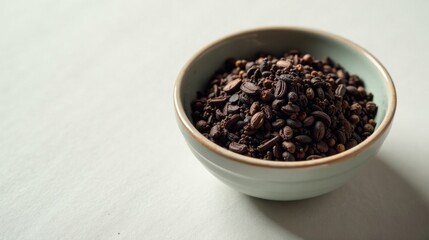 A bowl of roasted coffee beans and other dark-colored seeds