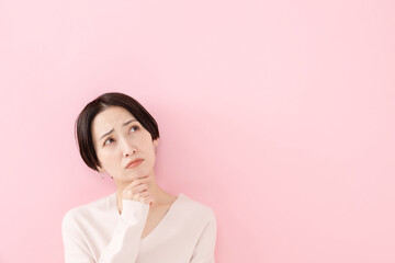 悩む・考える・困る女性・ピンクバック