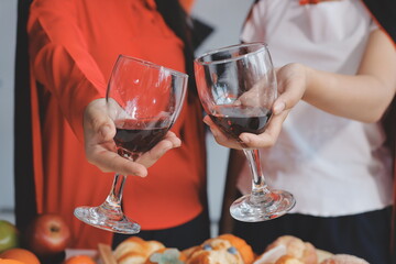 friendship, holiday and people concept - group of happy smiling friends in halloween costumes of vampire, devil, witch and cheetah at home party