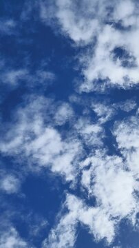 blue sky with rolling white clouds which is very bright during the day in vertical