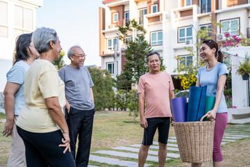 Naklejka premium Group of elderly people holding exercise mat with trainer in the garden.