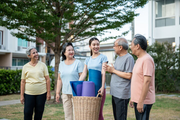 Group of elderly people holding exercise mat with trainer in the garden.