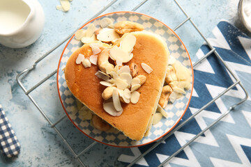Plate with tasty pancakes in shape of heart and nuts on blue background, closeup. Valentine's Day celebration
