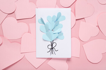 Composition with beautiful greeting card and paper hearts on pink background. Valentine's Day celebration