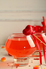 Glass of tasty cocktail with marmalade and hearts on white tile table, closeup. Valentine's Day celebration